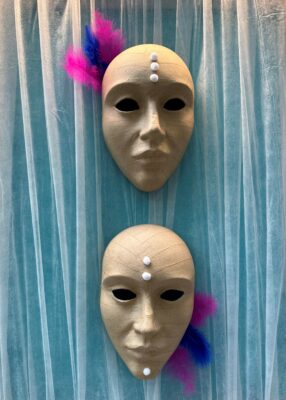 Leere Maske dekoriert mit Pompons und Federn